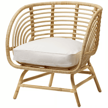 A light-colored rattan armchair with a curved back and armrests. It features a thick, white seat cushion. The frame is constructed from natural cane or bamboo, with woven details on the back and sides. The legs are also made of rattan and are angled outwards for stability. — 3D model