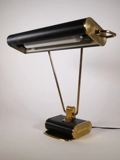 A stylish mid-century industrial desk lamp featuring a horizontal, rectangular, ribbed black shade and a matching ribbed black rectangular base. It is supported by two V-shaped polished brass arms that connect the shade to the base, with a central brass accent bracket. — 3D model