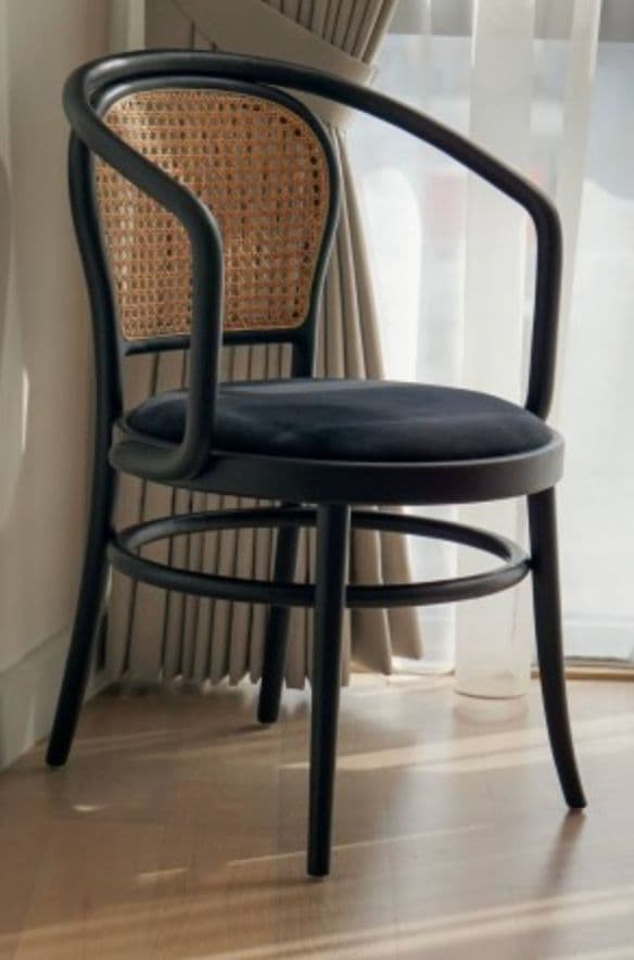 A modern armchair with a black bentwood frame and a cane backrest. The seat is upholstered in black fabric. The chair features curved armrests and four legs connected by a circular support. — 3D model