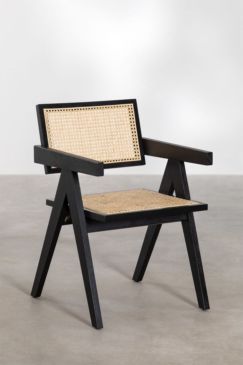A modern armchair with a black wooden frame and woven cane seat and backrest. The chair features a distinctive angular design with wide armrests and slightly splayed legs. The backrest is rectangular and incorporates a woven cane panel. The seat is also a woven cane panel. — 3D model