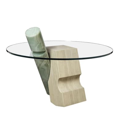 A contemporary coffee table featuring a circular glass top supported by an abstract sculptural base. The base is composed of two distinct elements: one is a light-colored, textured block with carved indentations, appearing to be travertine; the other is a cylindrical element with a veined, translucent green stone, likely onyx, integrated with the first block. The overall design is avant-garde and sculptural. — 3D model