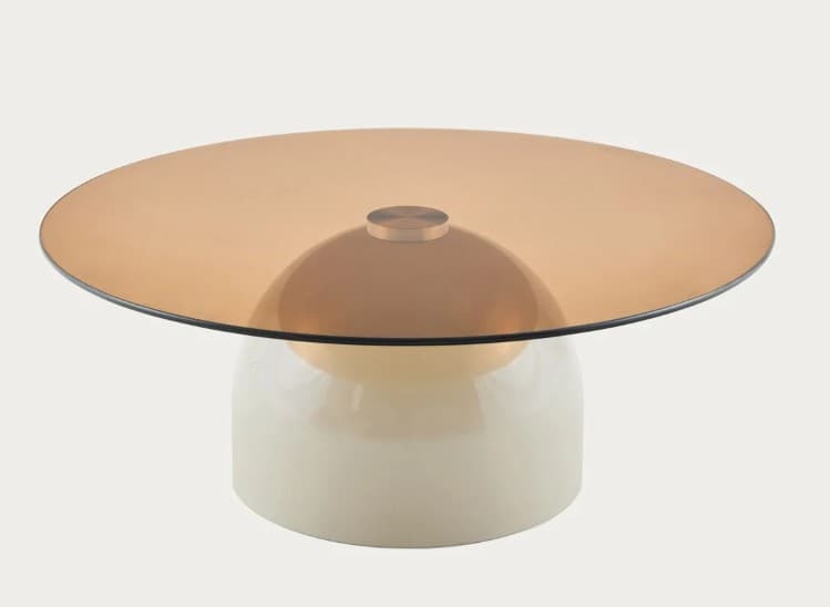 A coffee table with a round, amber-tinted glass top and a white, bulbous base. The base has a glossy finish and appears to be made of a solid material. A metallic accent piece connects the glass top to a domed structure that sits atop the base. — 3D model