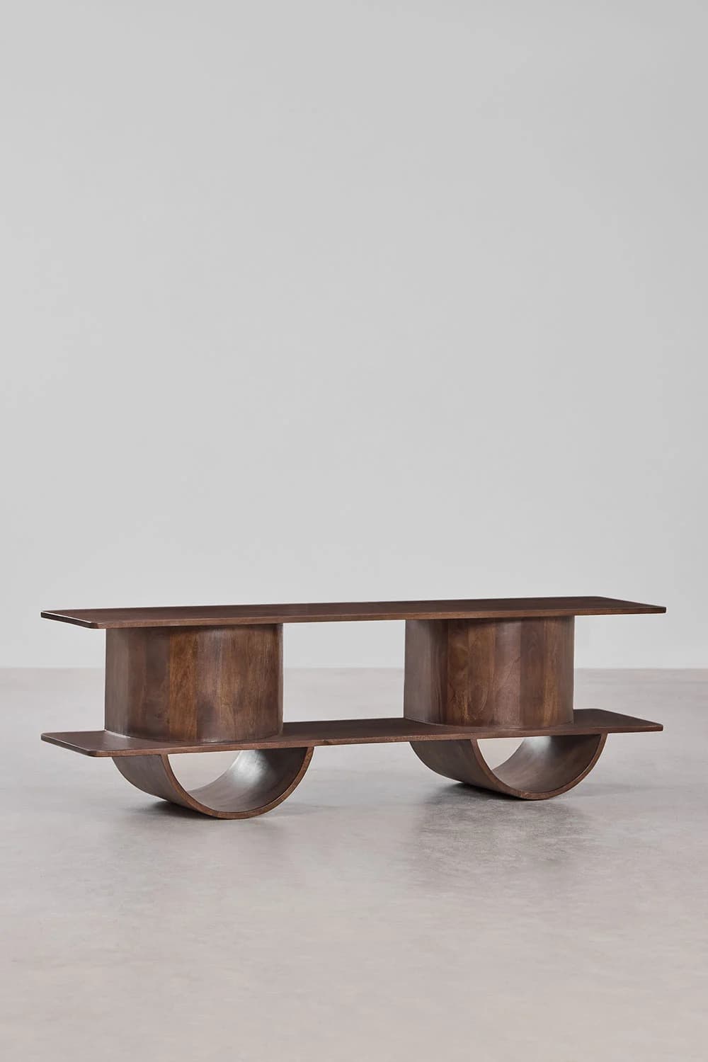 A contemporary coffee table with a distinct sculptural form. It features a rectangular top supported by two cylindrical vertical elements, each integrated with a curved base. A lower shelf connects the two curved bases, creating an open, layered structure. The design emphasizes clean lines and organic curves. — 3D model