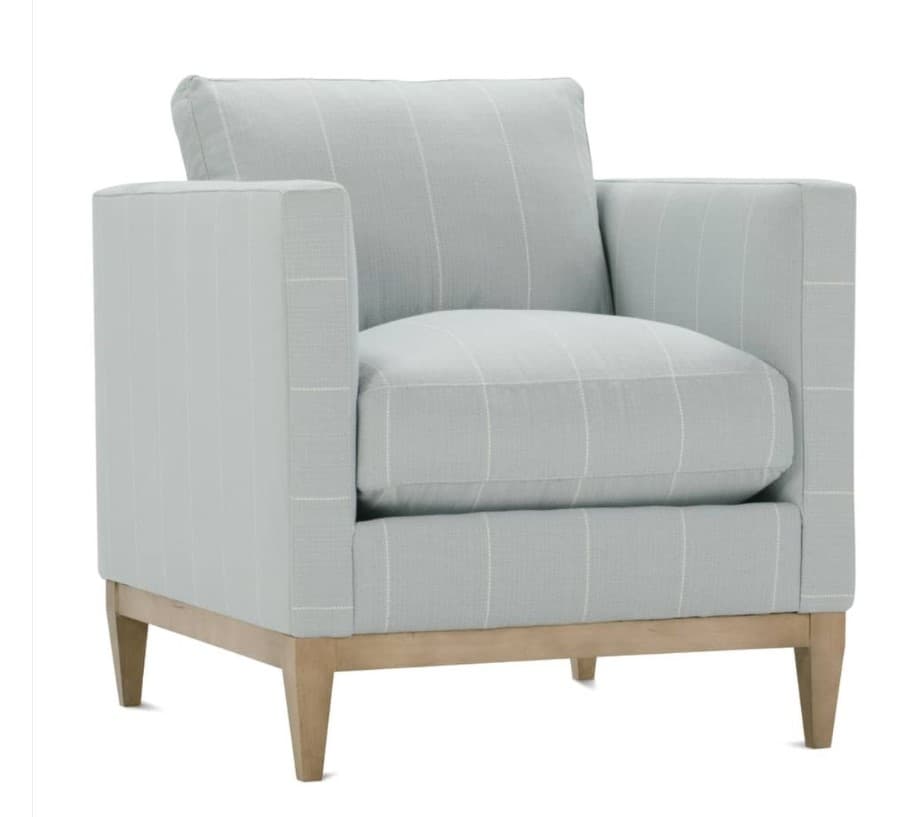 A single upholstered armchair with a clean, contemporary design. The chair features a padded seat and back cushion, as well as upholstered arms. The frame appears to be constructed with visible wooden legs and a base structure. The upholstery has a subtle checked pattern in light blue and white. — 3D model