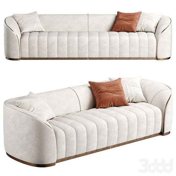 A modern, cream-colored sofa featuring channel tufting on the backrest and seat, rounded armrests, and a recessed wooden base. It is adorned with subtle metallic trim details and includes two rust-colored and two cream decorative pillows. — 3D model