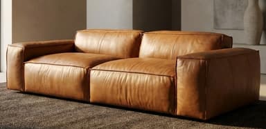 A modern two-seater sofa upholstered in tan leather, featuring a low profile, wide block arms, and prominent welted seams on its seat and back cushions. — 3D model