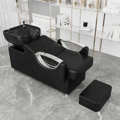 A professional salon shampoo chair with a black upholstered seat and back, an integrated black ceramic shampoo bowl, chrome faucet and sprayer, and a separate, matching black footrest. The chair features curved chrome armrests and a modern, commercial design. — 3D model