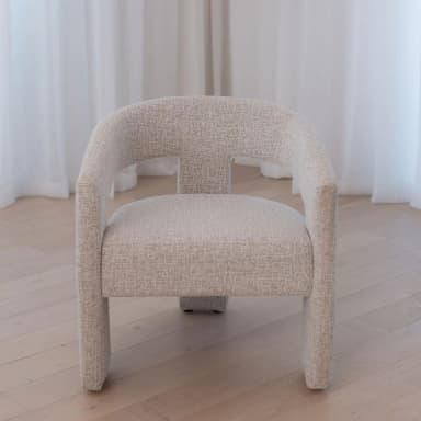 A modern armchair with a curved backrest and straight arms. The chair is upholstered in a textured fabric and features sturdy, rectangular legs. — 3D model