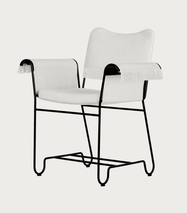 A contemporary armchair featuring a minimalist black metal tubular frame and upholstered seat, back, and armrests. The upholstery is off-white or cream-colored fabric, and the armrests are adorned with a distinctive fringe detail. — 3D model