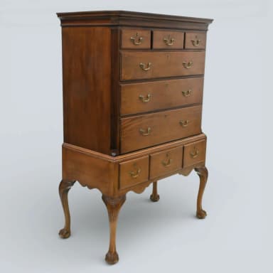 A traditional Queen Anne style highboy chest of drawers, constructed from medium-toned polished wood, featuring two stacked sections of multiple drawers with brass bail pulls, and supported by ornate cabriole legs ending in claw-and-ball feet. — 3D model