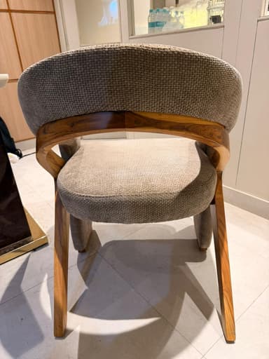 A contemporary armchair with a curved backrest and upholstered seat and arms. The frame appears to be constructed from wood, visible as a curved piece supporting the backrest. The upholstery is a textured fabric in a neutral tone. — 3D model
