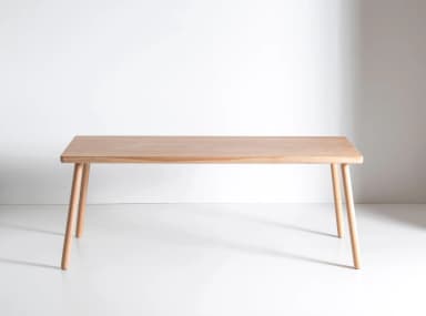 A light-toned wooden rectangular table featuring a smooth top with softly rounded corners and four tapered, cylindrical legs. — 3D model