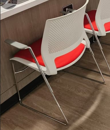 A modern armchair featuring a white perforated plastic backrest, a red upholstered seat, and a cantilever sled-style frame made of silver-colored metal. It includes fixed grey armrests. — 3D model
