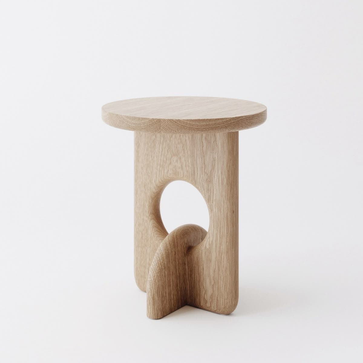 A modern, sculptural side table with a circular top and a unique, organically shaped pedestal base. The base features a large cutout and a twisted element, creating an artistic and visually dynamic form. The wood grain is prominently displayed, highlighting the natural material. — 3D model