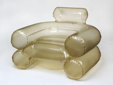 An inflatable armchair with a distinct translucent, smoky brown hue. The design features large, cylindrical forms for the armrests, base, and backrest, creating a plush and rounded silhouette. Seams are visible where the inflatable sections are joined, indicating its construction method. The material appears to be a flexible plastic or vinyl. — 3D model