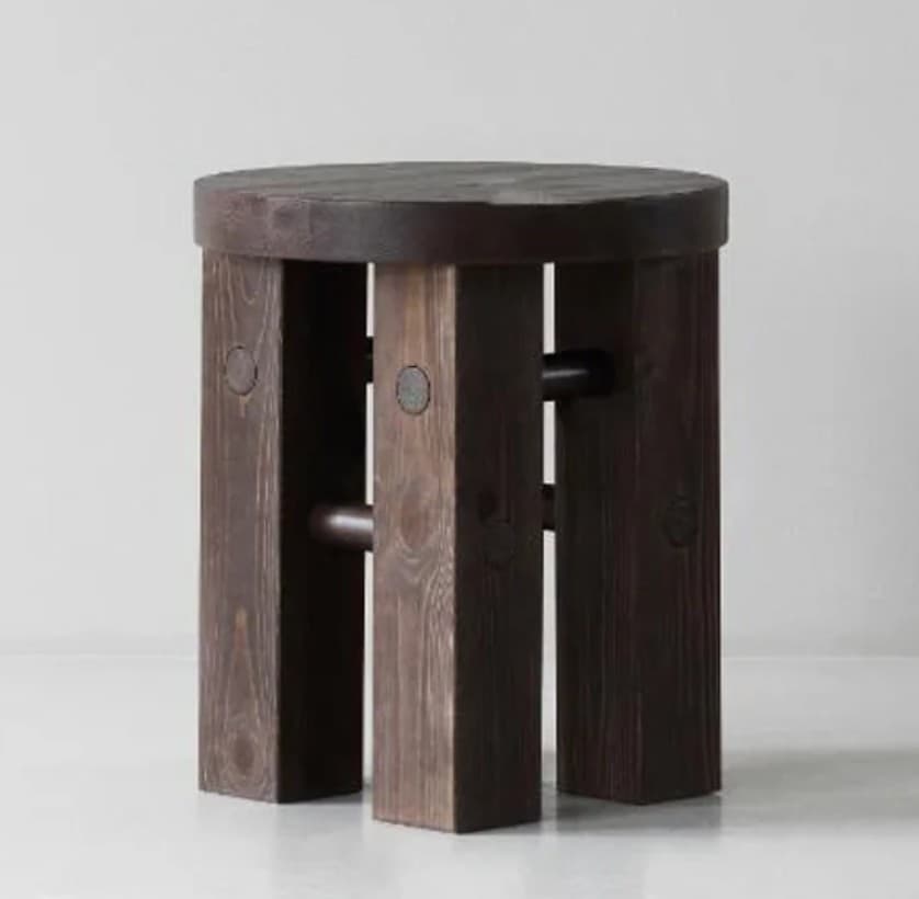 A round-seated stool constructed from dark-stained wood. It features multiple thick, rectangular plank legs arranged vertically, supporting a substantial circular top. The legs are stabilized by visible horizontal wooden dowels or rungs. The overall aesthetic is minimalist and rustic, highlighting the wood grain. — 3D model