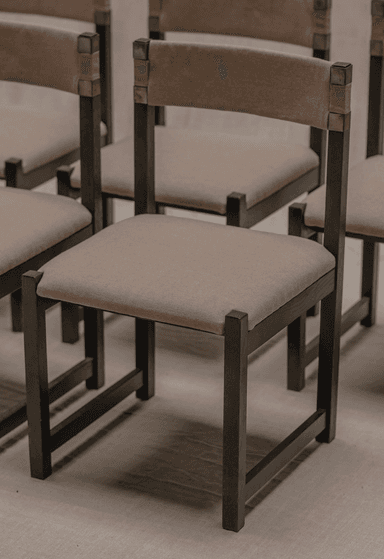 A contemporary chair with a dark metal frame and upholstered seat and back. The frame has a minimalist design with straight lines. The seat and back are upholstered in a light brown fabric. Metal brackets connect the upholstered backrest to the vertical supports of the frame. — 3D model