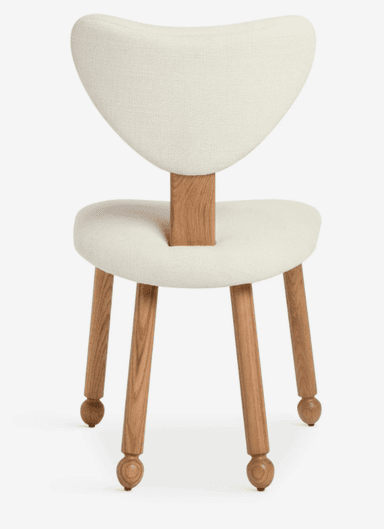 An armless dining chair featuring an off-white upholstered seat and a distinctive sculpted backrest. The backrest is connected to the seat by a rectangular wooden support. The chair stands on four tapered wooden legs, each terminating in a spherical foot detail. The upholstery appears to be a textured fabric, possibly boucle or a similar weave, in a light cream or off-white color. The wood has a natural finish, showcasing its grain. — 3D model
