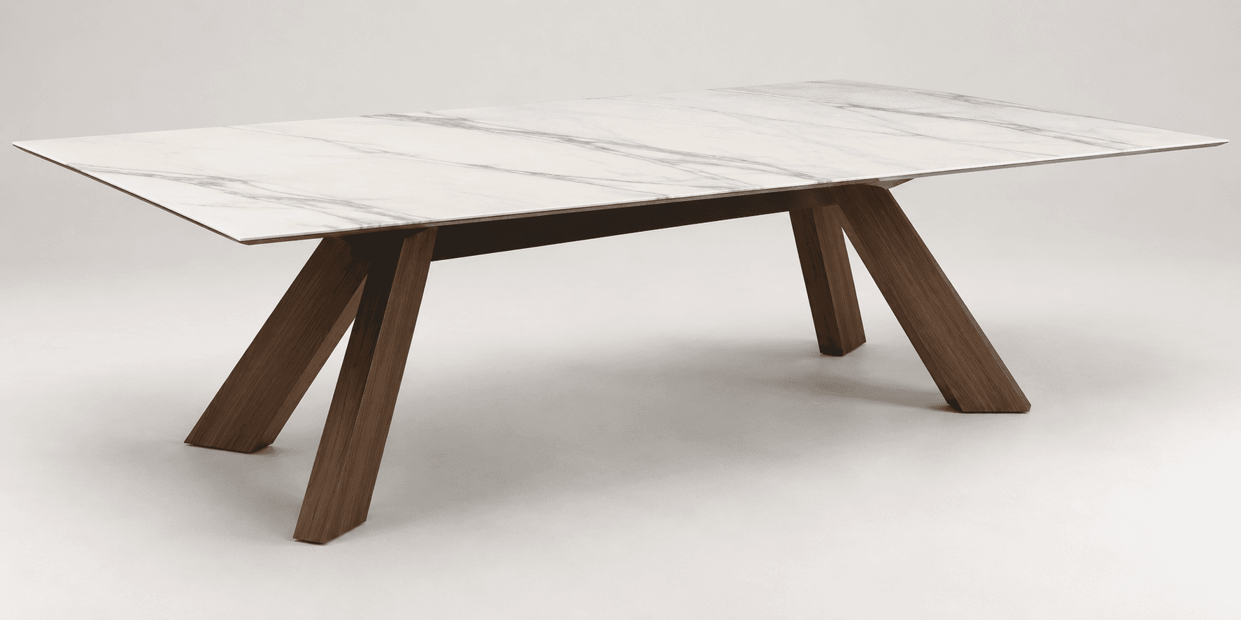 A modern rectangular dining table featuring a white top with a grey marble-effect pattern. The tabletop appears thin and is supported by a dark, possibly metal, sub-frame. The table base consists of two sets of angled, solid wooden legs, arranged in an A-frame or trestle style, finished in a warm brown tone. The overall design is sleek and contemporary. — 3D model