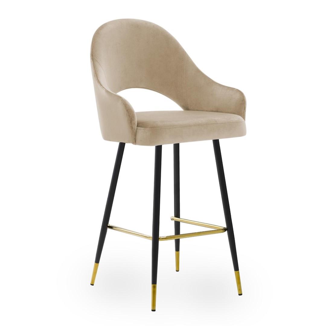 A bar stool with a beige velvet seat and back. The stool has a black metal frame with gold accents on the legs and a footrest.