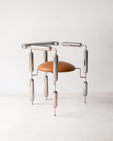A striking postmodern accent chair featuring a highly polished tubular chrome frame and a circular, tan upholstered seat. The frame is constructed from segmented chrome tubes connected by smaller rods and spherical joints, creating a unique, sculptural silhouette. The design is minimalist yet highly stylized, resembling an avant-garde artistic creation with functional seating. The seat appears to be made of leather or a high-quality leatherette. — 3D model