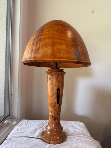 A distinctive mushroom-shaped table lamp crafted from highly figured wood, featuring a smooth, domed cap and a tapering cylindrical stem with a flared base. The stem includes irregular, darker, possibly epoxy-filled voids or inlays, adding a unique organic detail to the design. — 3D model