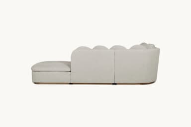 A modular sectional sofa with a chaise lounge. The sofa features a low profile with square seat cushions and rounded back cushions arranged in a series. It has a light-colored fabric upholstery and a visible wooden base. — 3D model