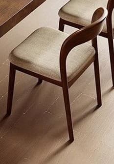 A contemporary dining set featuring a large rectangular dining table made of solid dark wood with rounded corners and a robust trestle base. The set includes six matching dining chairs with curved wooden backrests and light beige upholstered seats. — 3D model