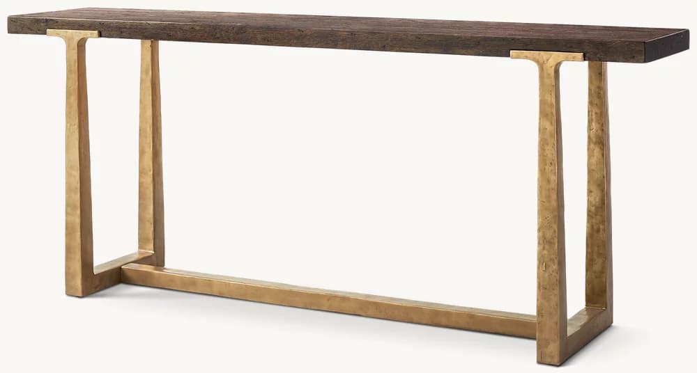 A rectangular console table featuring a rustic dark wood plank top supported by two hammered brass-toned metal bases. The bases are inverted U-shapes connected by a horizontal stretcher bar at the floor level, creating a sturdy and open design. — 3D model