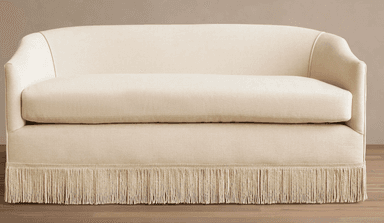 A contemporary loveseat upholstered in a light cream fabric, featuring a curved back, gently rolled armrests, a single seat cushion, and a distinctive decorative fringe skirt along the entire base. — 3D model