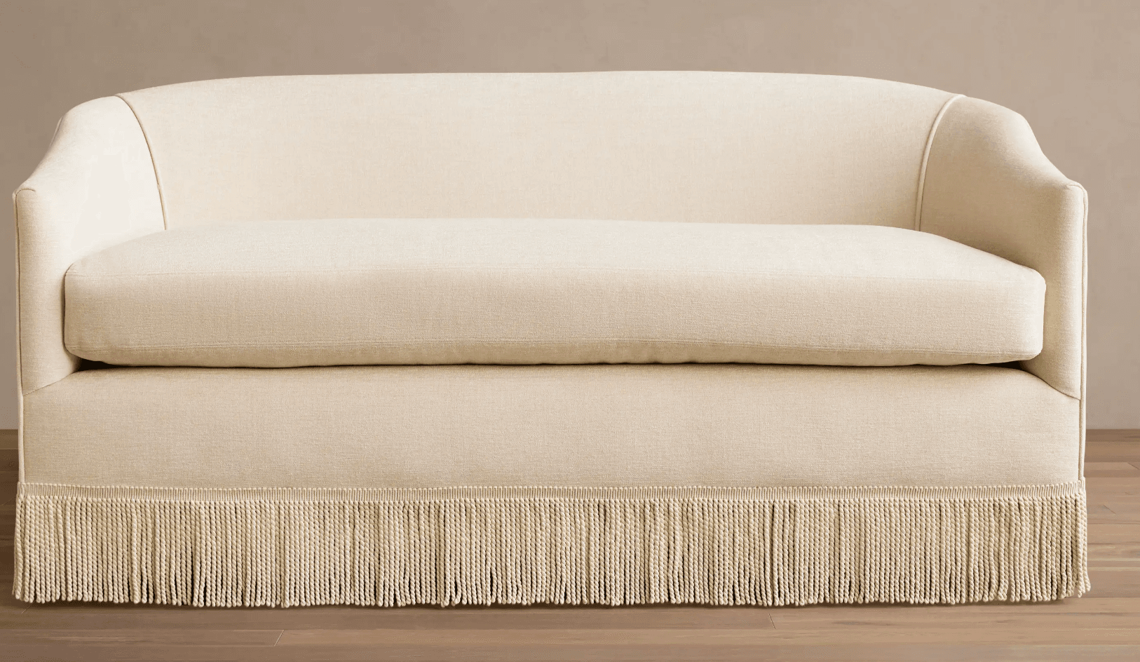A contemporary loveseat upholstered in a light cream fabric, featuring a curved back, gently rolled armrests, a single seat cushion, and a distinctive decorative fringe skirt along the entire base. — 3D model