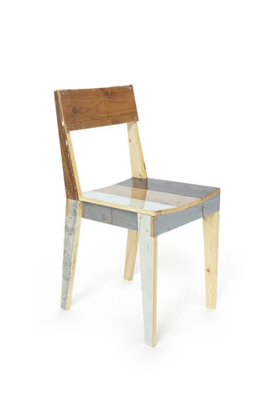 An armless side chair constructed from various pieces of reclaimed or repurposed wood, exhibiting a patchwork aesthetic. The chair features a rectangular backrest and a flat seat, with some wood pieces retaining a natural finish and others painted in distressed shades of grey, white, and light blue. It has a simple, straight-legged design with visible fasteners. — 3D model
