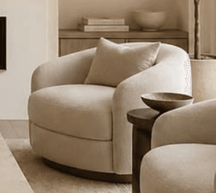 An upholstered barrel-shaped chair with a rounded back, integrated arms, and a loose back cushion, featuring a textured cream fabric and set on a dark, recessed swivel base. — 3D model