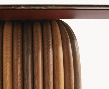 An oval coffee table featuring a multi-toned marble top and a distinctive cylindrical base constructed from numerous vertical, rounded wooden slats in varying natural wood hues, resting on a subtle reddish-brown plinth. — 3D model
