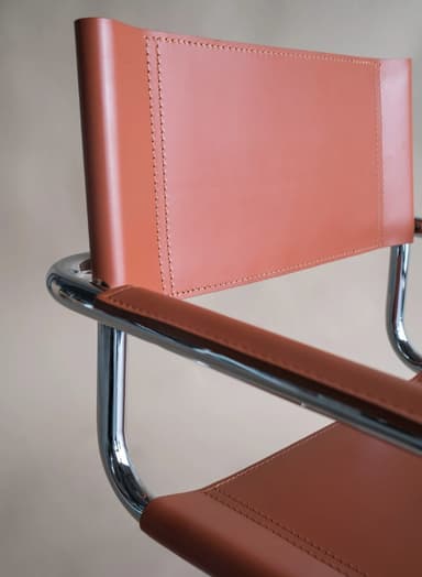 A modern armchair with a tubular chrome frame and leather upholstery. The seat and backrest are made of brown leather straps, and the armrests are also upholstered in leather. The frame is constructed from bent tubular metal, forming legs that extend upwards to support the seat and back. — 3D model