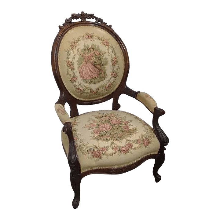 An upholstered accent chair with a dark wood frame. The chair features a high, oval-shaped backrest and a rounded seat. Both the backrest and seat are covered in a light-colored fabric with a floral pattern. The backrest is further decorated with a central oval tapestry depicting a couple in period attire. The wooden frame exhibits ornate carvings, particularly on the crest rail and cabriole legs. The armrests are padded and covered in a matching fabric. — 3D model