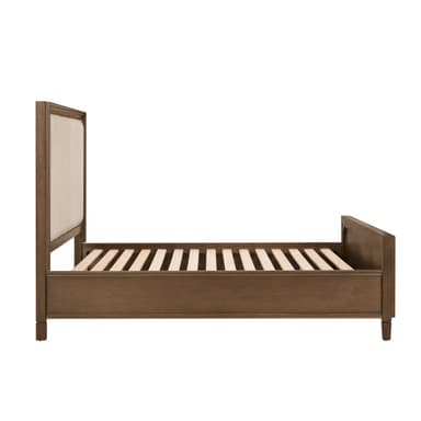 A transitional style bed frame featuring a wooden structure with upholstered panels on both the headboard and footboard. The upholstery is a light, neutral fabric, bordered by decorative nailhead trim. The frame has a warm brown finish, and the headboard is slightly taller than the footboard. It includes support slats for a mattress. — 3D model