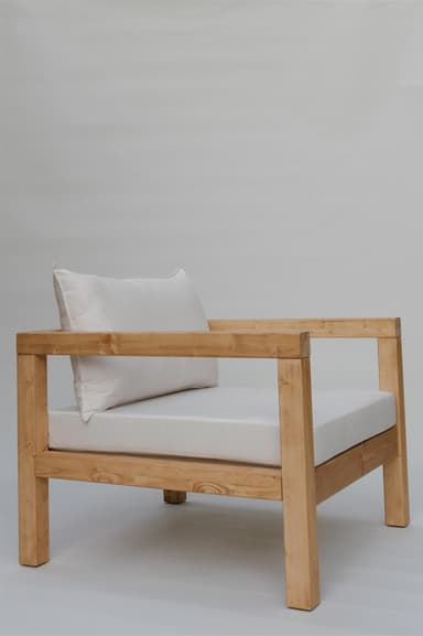 A single armchair with a solid wood frame and upholstered cushions. The frame consists of thick, square-profile wooden beams for the legs, base, and arms. The seat and back are padded with white cushions. A rectangular lumbar pillow is placed against the back cushion. — 3D model