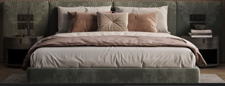 A contemporary upholstered platform bed featuring a wide, extended headboard that seamlessly integrates two round nightstands on either side. The bed frame and headboard are covered in a dark green, soft-textured fabric, suggesting velvet or suede. The headboard also incorporates electrical outlets or light switches, indicating functionality beyond mere aesthetics. The bedding consists of white sheets and pillows, accented with blush pink and light brown throw pillows and a matching throw blanket, contrasting with the dark green upholstery. — 3D model