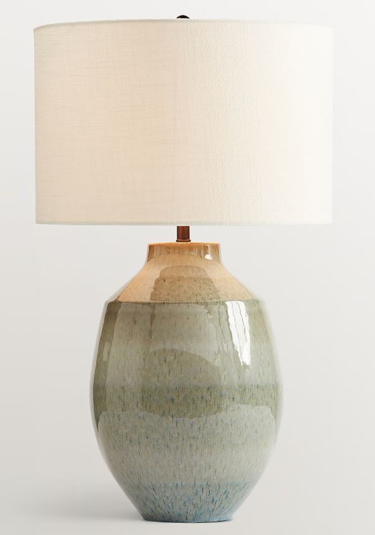 A table lamp with a ceramic base and a fabric shade. The base is bulbous with a tapered neck and features a glazed finish with a gradient of earth tones, transitioning from beige at the top to green and blue at the bottom. The shade is cylindrical and made of a light-colored fabric. — 3D model