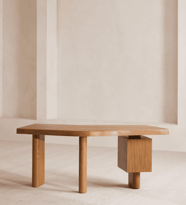 A contemporary desk featuring an irregularly shaped wooden tabletop supported by cylindrical legs and an integrated three-drawer pedestal. The main structure appears to be solid light-toned wood, possibly oak, while the drawer fronts are made from a contrasting darker burl wood veneer, adding a distinctive visual element. The design is minimalist and sculptural. — 3D model