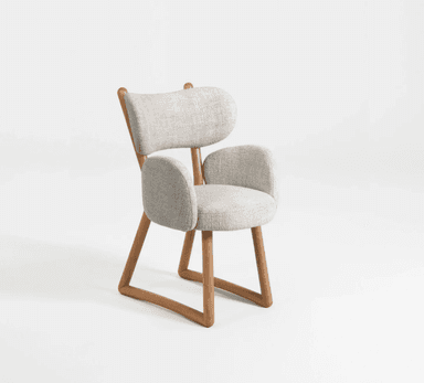 A modern armchair with a light grey upholstered seat, backrest, and armrests, supported by a natural wood frame. The frame has a distinctive angular design, particularly at the legs and where the backrest is supported. The upholstery has a textured fabric weave. — 3D model
