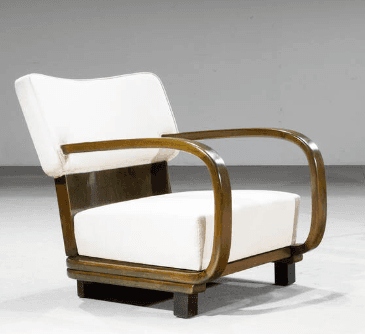 A modern armchair featuring a tubular armrest and a solid base. The seat and backrest are upholstered in a light-colored fabric, contrasting with the dark wood frame and armrests. The design exhibits a sleek, curved aesthetic. — 3D model