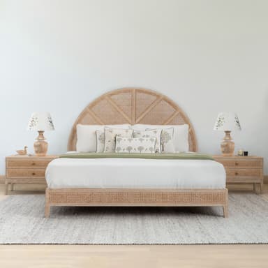 This image displays a modern platform bed crafted from light-toned wood and featuring intricate cane webbing. The most prominent feature is its semicircular headboard, which is divided into sections with the cane material creating a fan-like pattern. The bed frame's side rails also incorporate cane webbing, matching the headboard. The bed is dressed with a white mattress, white sheets, a light green throw, and several decorative pillows with nature-inspired patterns and green piping. — 3D model