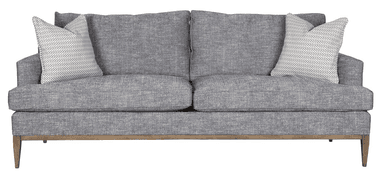 A sofa upholstered in a textured gray fabric. It features a wooden base frame and legs with a natural wood finish. The backrest is composed of two distinct cushions, and an accent pillow with a geometric pattern in white and gray is visible on the left side. — 3D model