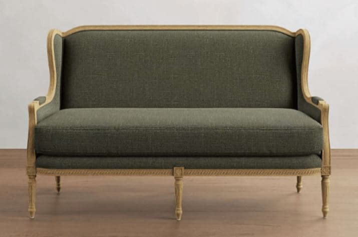 A two-seater sofa with a high, curved back and sloping arms. The frame is exposed wood, featuring a light-colored finish and decorative carving along the top edge and base. The upholstery is a textured, dark green fabric. The sofa has four wooden legs, with the front legs exhibiting a tapered, turned design. — 3D model