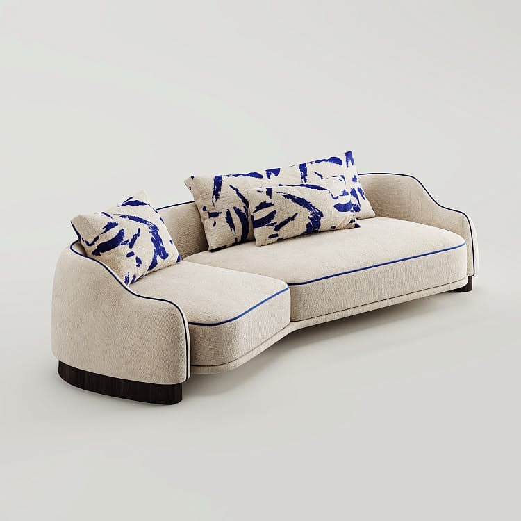A contemporary curved sofa with an integrated chaise lounge, upholstered in a light beige textured fabric with blue piping. It features a low-profile design and rests on a dark wooden base. Two accent pillows with a blue abstract pattern are included. — 3D model
