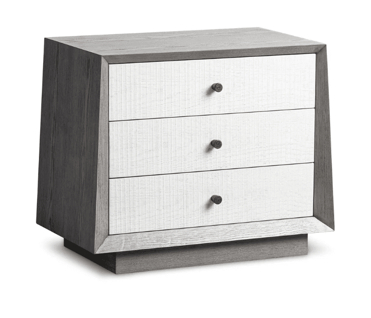 A contemporary nightstand with a distinctive design. It features a grey-toned wooden frame with a weathered texture and a contrasting white front panel. The front is composed of three drawers, each with a small, round, brown knob for a handle. The nightstand is elevated by a solid base with a beveled edge. — 3D model