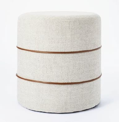 A contemporary cylindrical ottoman featuring off-white textured fabric upholstery and two thin, dark brown decorative bands encircling its body. — 3D model