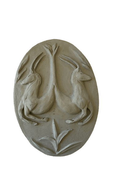 An oval-shaped relief sculpture featuring a symmetrical design of two stylized horned animals, resembling gazelles or antelopes, facing outwards from a central plant or tree motif. The sculpture has a pale, off-white or light gray matte finish, suggesting a material like plaster or a stone composite. The figures are rendered in low relief, providing depth and texture to the decorative piece. — 3D model